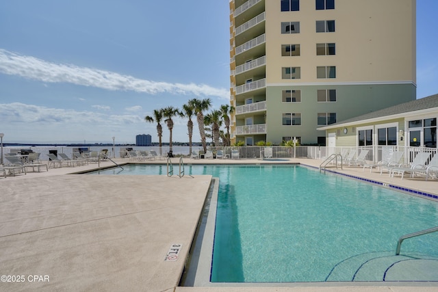 community pool with a patio area and fence