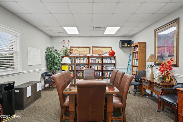 dining space with a drop ceiling, carpet, and visible vents