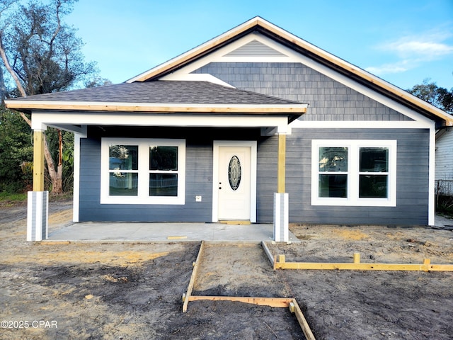 view of front of home with uncovered parking and roof with shingles