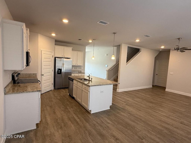 kitchen with sink, an island with sink, pendant lighting, stainless steel appliances, and white cabinets