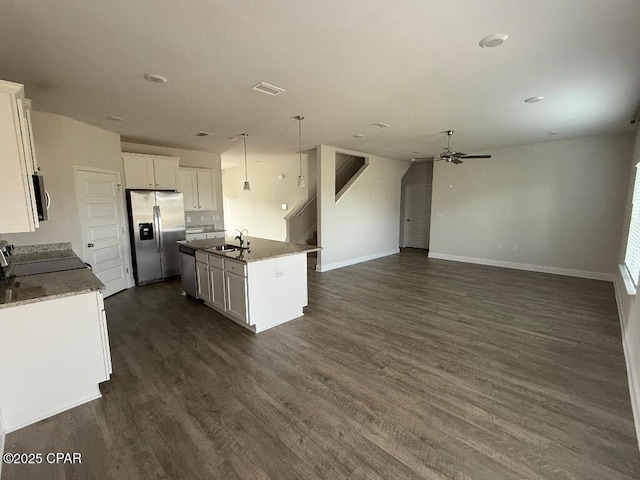 kitchen with dark wood-style floors, stainless steel appliances, open floor plan, a kitchen island with sink, and white cabinetry