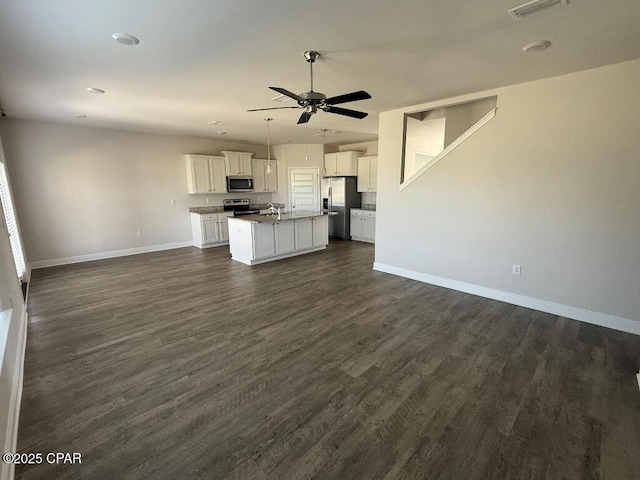 kitchen with stainless steel appliances, a ceiling fan, white cabinetry, open floor plan, and a center island with sink