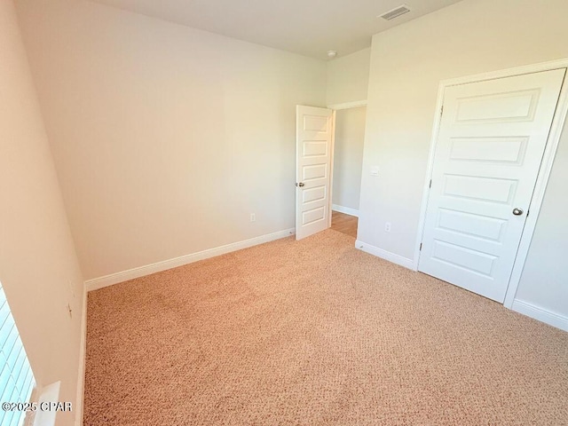 unfurnished bedroom featuring baseboards, visible vents, and light colored carpet