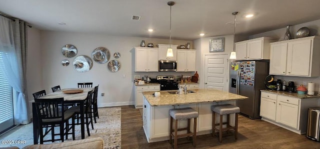 kitchen with stainless steel appliances, an island with sink, white cabinets, and pendant lighting