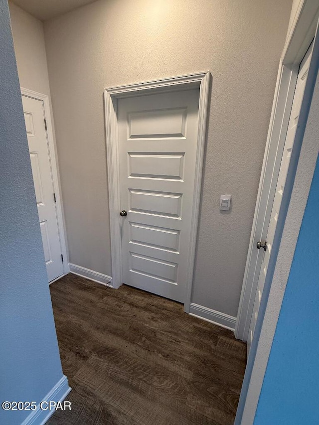 hallway featuring dark wood finished floors and baseboards