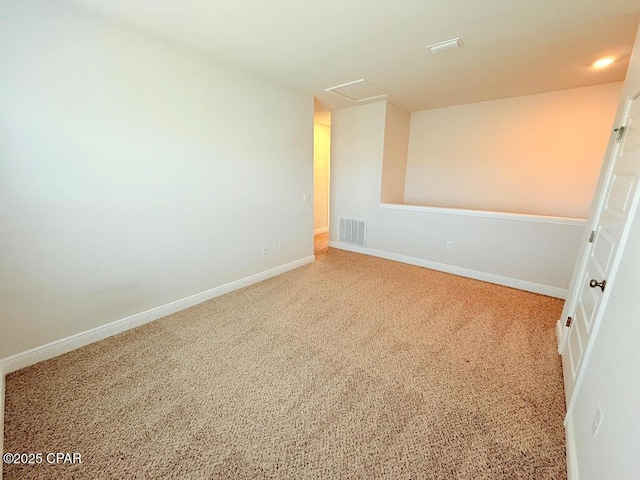 carpeted spare room with attic access, baseboards, and visible vents