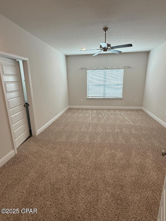 empty room featuring ceiling fan, carpet floors, a textured ceiling, and baseboards