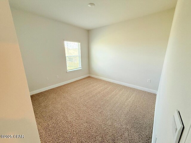 unfurnished room featuring light carpet and baseboards