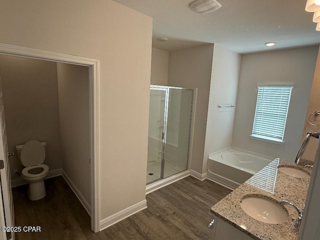 full bathroom featuring wood-type flooring, separate shower and tub, vanity, and toilet