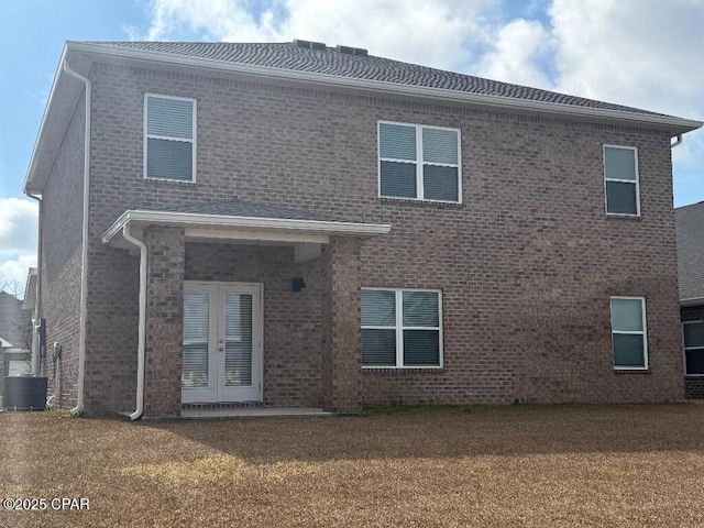 rear view of house with central AC unit, a yard, and french doors