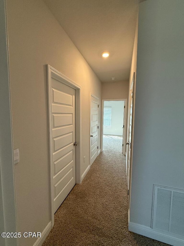 corridor featuring carpet, visible vents, and baseboards