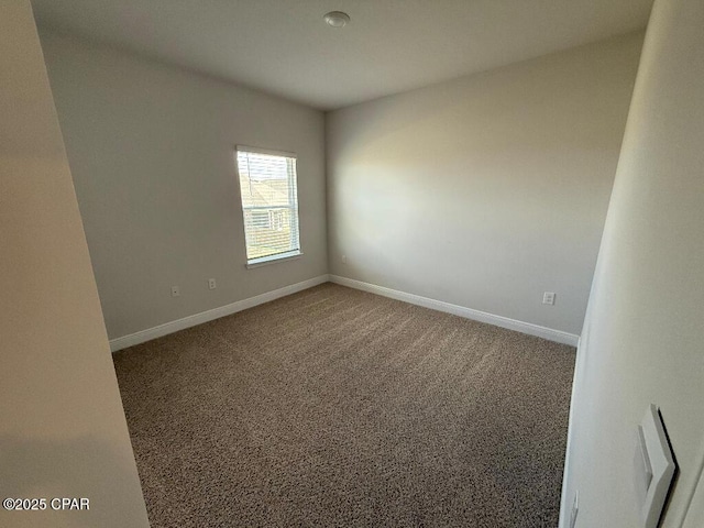 carpeted spare room featuring baseboards