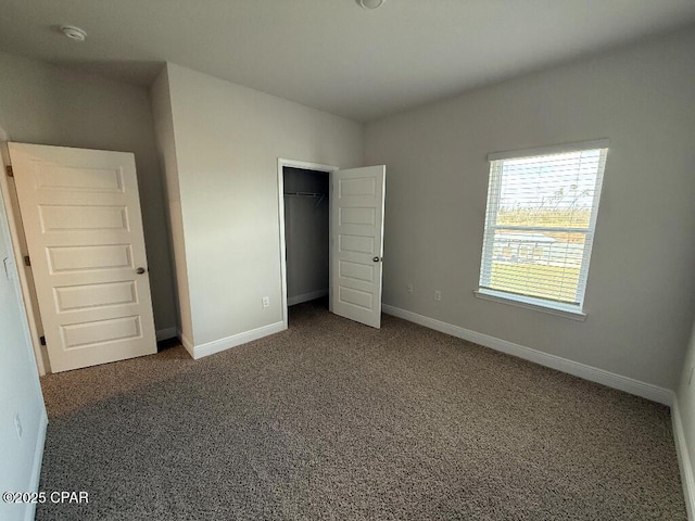 unfurnished bedroom featuring dark colored carpet, a closet, and baseboards