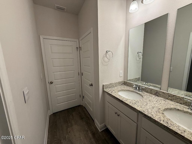 full bathroom featuring double vanity, visible vents, a sink, and wood finished floors