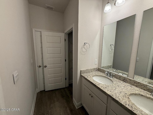 bathroom with double vanity, wood finished floors, a sink, and visible vents