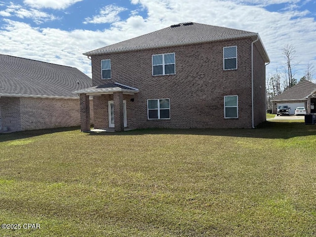 rear view of house featuring brick siding and a lawn