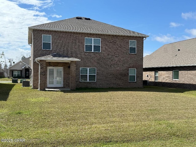 rear view of property with brick siding, central AC unit, a lawn, and french doors