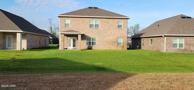 rear view of house with brick siding and a yard