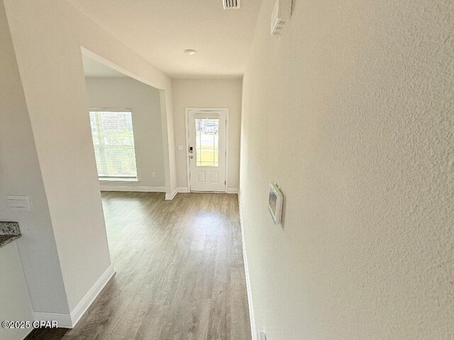 doorway with dark wood-type flooring, visible vents, and baseboards