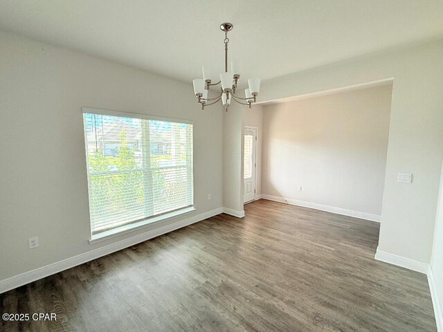 empty room with dark wood-style floors, baseboards, and a chandelier