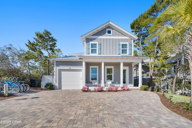 view of front of house with a garage, metal roof, decorative driveway, a porch, and board and batten siding