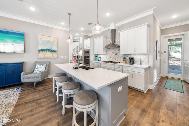 kitchen with stainless steel appliances, white cabinetry, hanging light fixtures, light countertops, and wall chimney exhaust hood