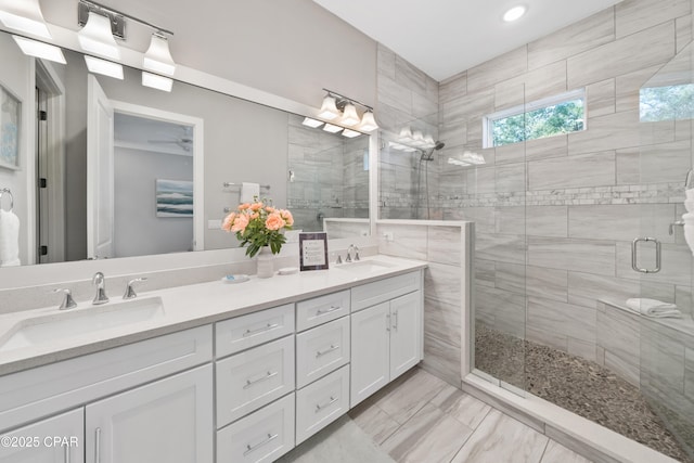 bathroom featuring double vanity, a stall shower, and a sink