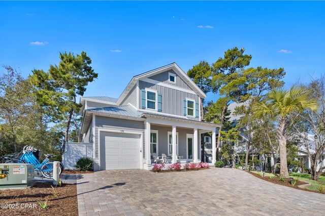 view of front facade featuring board and batten siding, metal roof, a porch, and decorative driveway