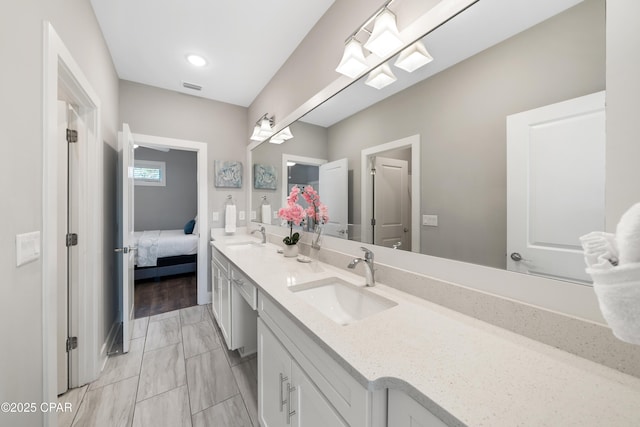 ensuite bathroom with double vanity, connected bathroom, visible vents, and a sink