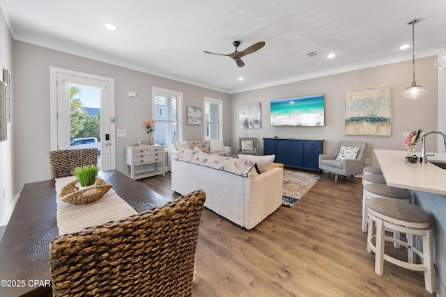 living area with recessed lighting, wood finished floors, visible vents, and crown molding