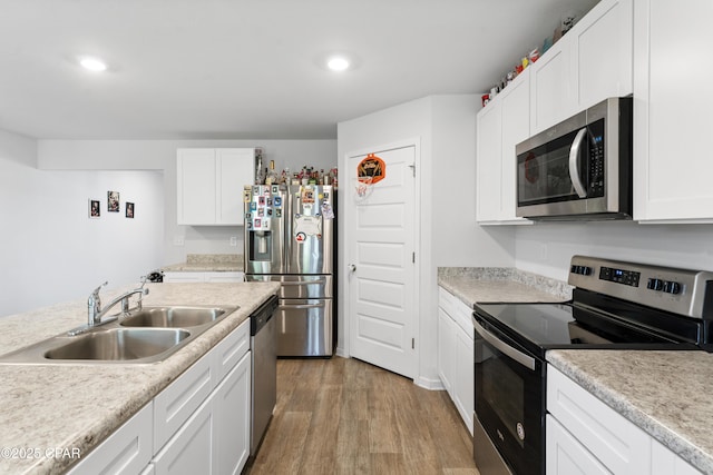 kitchen with white cabinetry, stainless steel appliances, sink, and light hardwood / wood-style flooring