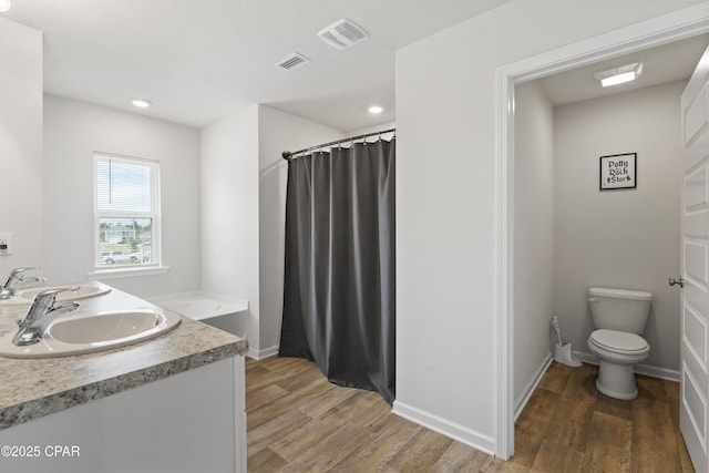 bathroom with hardwood / wood-style flooring, vanity, toilet, and a bathing tub