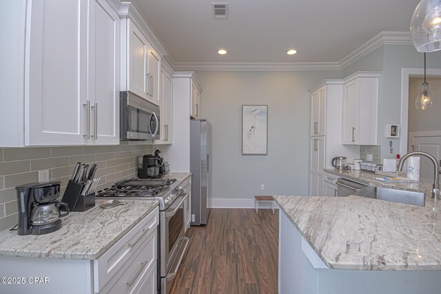 kitchen with stainless steel appliances, kitchen peninsula, hanging light fixtures, and white cabinets