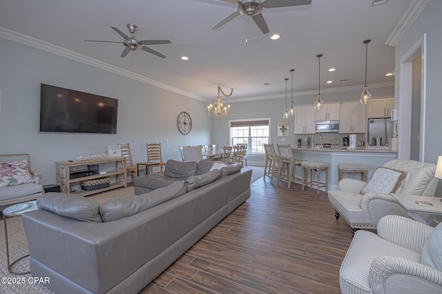 living room featuring sink, ornamental molding, dark hardwood / wood-style floors, and ceiling fan with notable chandelier