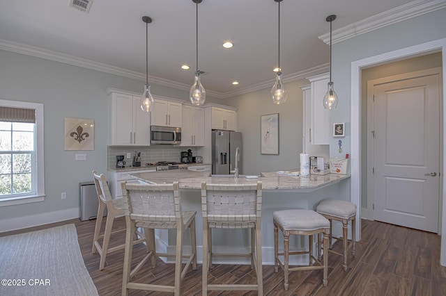 kitchen featuring pendant lighting, appliances with stainless steel finishes, white cabinetry, decorative backsplash, and kitchen peninsula