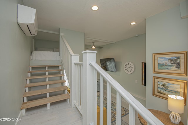 staircase with hardwood / wood-style floors, a wall mounted AC, and ceiling fan