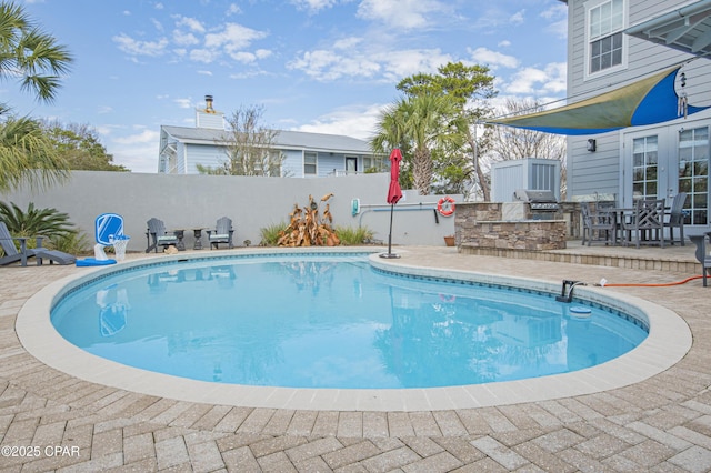 view of pool featuring an outdoor kitchen, grilling area, and a patio area