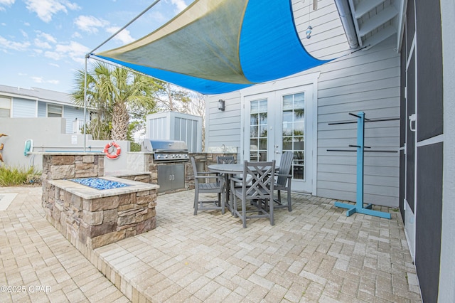 view of patio / terrace with french doors, area for grilling, a grill, and a fire pit