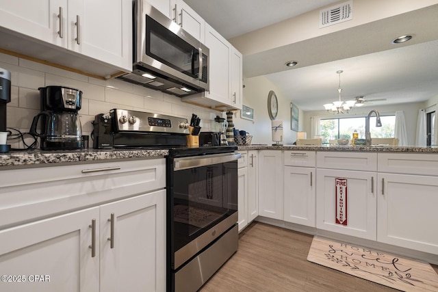 kitchen featuring backsplash, appliances with stainless steel finishes, light stone countertops, and white cabinets