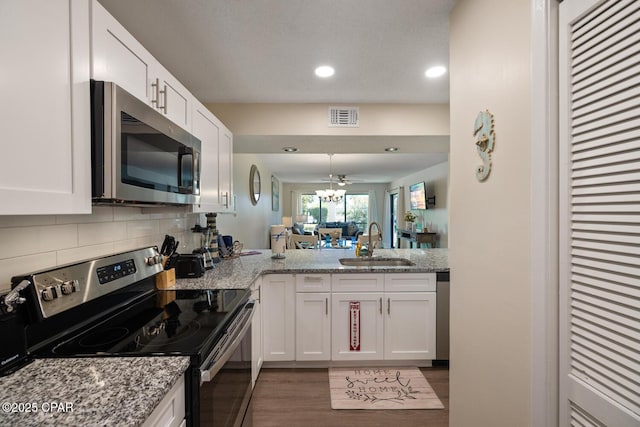 kitchen with light stone countertops, white cabinetry, appliances with stainless steel finishes, and sink