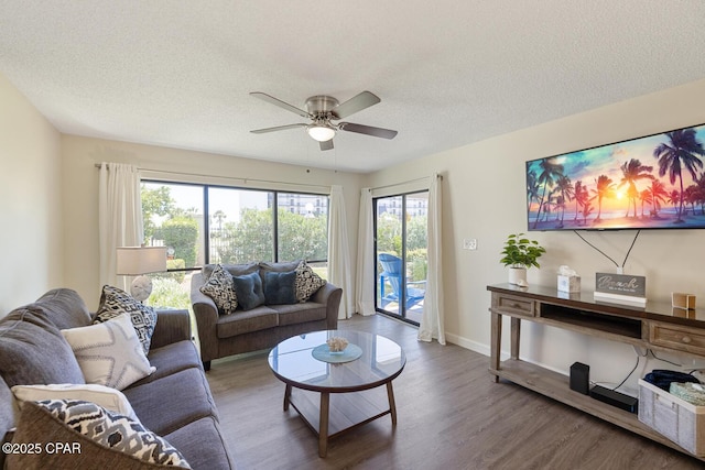 living room featuring hardwood / wood-style flooring, ceiling fan, and a textured ceiling