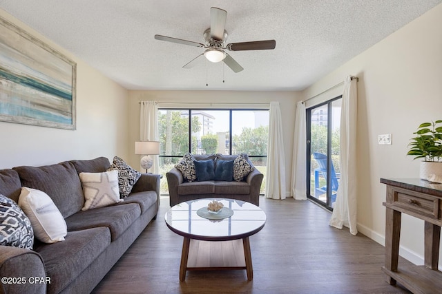 living room featuring ceiling fan, dark hardwood / wood-style floors, and a textured ceiling