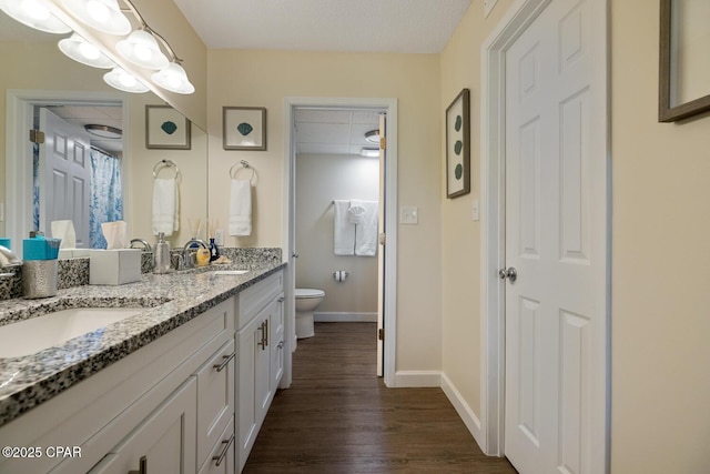 bathroom featuring hardwood / wood-style flooring, a paneled ceiling, vanity, and toilet