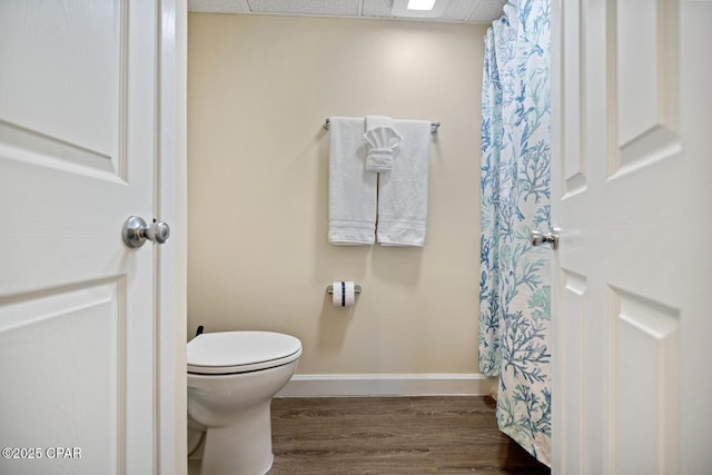 bathroom featuring wood-type flooring, a paneled ceiling, and toilet