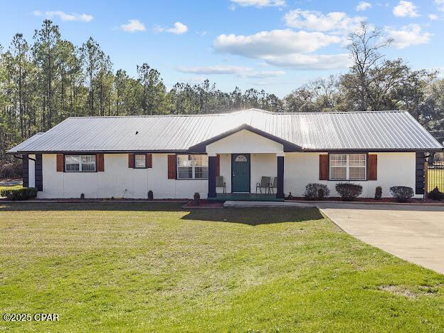 ranch-style home with metal roof and a front lawn