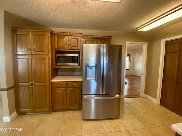 kitchen featuring appliances with stainless steel finishes, a textured ceiling, and light tile patterned floors