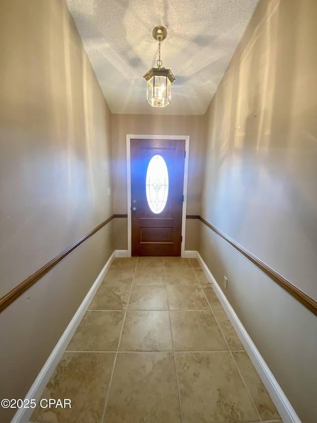 entryway with an inviting chandelier, tile patterned floors, and a textured ceiling