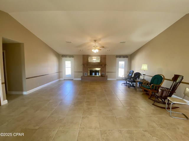 sitting room featuring light tile patterned flooring, lofted ceiling, ceiling fan, and a brick fireplace