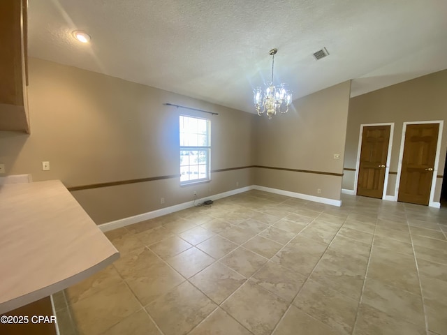 unfurnished dining area with a notable chandelier, vaulted ceiling, a textured ceiling, and light tile patterned flooring