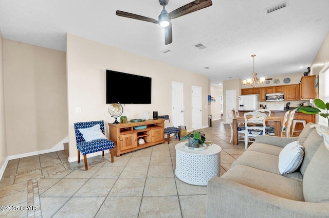 tiled living room with ceiling fan with notable chandelier and a textured ceiling